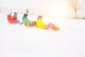 Side view of young friends sledging on snow covered slope