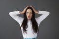 Portrait of young frowning displeased woman on gray background