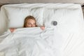 Young funny beautiful woman looking at alarm clock while lying on bed Royalty Free Stock Photo