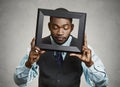 Portrait young funny executive man sticking head in picture frame looking around Royalty Free Stock Photo