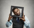 Portrait young funny executive man sticking head in picture frame looking around Royalty Free Stock Photo