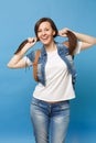 Portrait of young funny pretty smiling woman student in white t-shirt, denim clothes with backpack holding ponytails Royalty Free Stock Photo