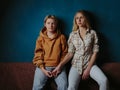 Portrait of young gay couple, girls lesbian sitting and holding hands on background of blue wall. Concept of love, gay marriage an Royalty Free Stock Photo