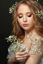 Portrait of young gentle woman with white flowers on black background