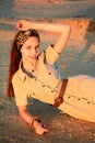 Portrait of a young girl in a beige dress lying on the sand in the sunlight Royalty Free Stock Photo