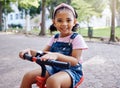 Portrait, young girl on bike in park and happy child outdoor with nature and freedom, smile while riding. Travel Royalty Free Stock Photo