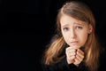 Portrait of a young girl on a black background. She is prayerfully prayed. She asks God for help