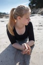 Portrait of young girl in black dress with long blonde hair lying on beach Royalty Free Stock Photo