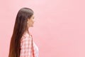 Portrait of young girl in checkered shirt posing  over pink studio background. Side view Royalty Free Stock Photo