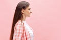 Portrait of young girl in checkered shirt posing  over pink studio background. Side view Royalty Free Stock Photo