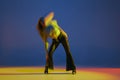 Portrait of young girl dancing heels dance in stylish clothes over blue background in neon light with mixed lights Royalty Free Stock Photo