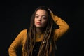 Portrait of a young girl with dreads on black background.