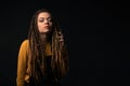 Portrait of a young girl with dreads on black background.