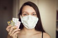 Portrait of young girl with ear loop face mask with pharma drugs - blisters - in hand