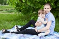 Portrait of young girl embracing her infant sister, girls sitting on blanket on green grass in park Royalty Free Stock Photo