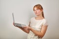 Portrait of young girl with ginger hair in ponytail dressed in casual white blouse holding a laptop computer Royalty Free Stock Photo