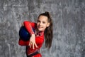 A portrait of young girl gymnast in a red suit makes exercise with a ball against a gray wall. She holds the ball Royalty Free Stock Photo