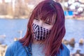 Portrait of a young girl in a homemade protective mask against coronavirus covid-19 and red hair fluttering in the wind.