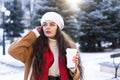 portrait of a young girl with hot fragrant coffee in her hands bending her on a cold day