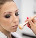 Portrait of young girl with makeup and hand makeup artist with brush