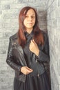 Portrait of a young girl without makeup on her face in a black jacket against a gray brick wall. Royalty Free Stock Photo