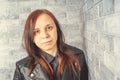 Portrait of a young girl without makeup on her face in a black jacket against a gray brick wall. Royalty Free Stock Photo