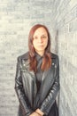 Portrait of a young girl without makeup on her face in a black jacket against a gray brick wall. Royalty Free Stock Photo