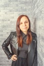 Portrait of a young girl without makeup on her face in a black jacket against a gray brick wall. Royalty Free Stock Photo