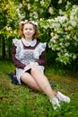 Portrait of a young girl in an old school uniform of the USSR with a black dress and a white apron. Teenager in the Park among the