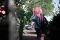 Portrait of young girl with pink hair sniffing rose flower.