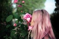 Portrait of young girl with pink hair sniffing rose flower.