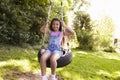 Portrait Of Young Girl Playing On Tire Swing In Garden Royalty Free Stock Photo