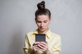 Portrait of young girl playing video games on smartphone, over white background. Dressed in yellow shirt Royalty Free Stock Photo