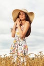 Portrait of a young girl posing in a summer dress on a background of a field with ripe wheat Royalty Free Stock Photo