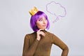 Portrait young girl with purple hairstyle in luxury dress in studio. She wears gold crown, looking to side.