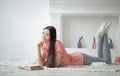 Portrait of young girl reading book lying on floor in living room Royalty Free Stock Photo