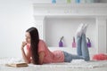 Portrait of young girl reading book lying on floor in living room Royalty Free Stock Photo