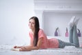 Portrait of young girl reading book lying on floor in living room Royalty Free Stock Photo