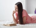 Portrait of young girl reading book lying on floor in living room Royalty Free Stock Photo