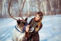 Portrait of a young girl with a reindeer in the winter