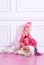 Portrait of young girl, sad princess wearing elegant pink clothes, and peruke holding candies over luxury interior Royalty Free Stock Photo
