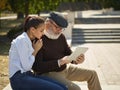 Portrait of young girl sitting with grandfather at park