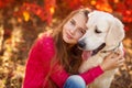 Portrait of Young girl sitting on the ground with her dog retriever in autumn scene