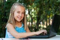 Cute girl doing homework on laptop outdoors. Royalty Free Stock Photo