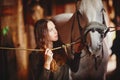 Portrait of a young girl in a village stables with a horse. Dressed in folk style Royalty Free Stock Photo