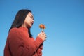 Portrait young girl wear orang swater with orang flower with blue sky background Royalty Free Stock Photo