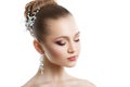 Portrait of a young girl with a wedding makeup. Perfect skin, smooth hair, large crystal earrings and hair ornament. Isolation on