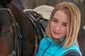 Portrait of a young girl with white hair next to a brown horse. The girl holds the horse. Close-up Royalty Free Stock Photo