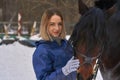 Portrait of a young girl with white hair next to a brown horse. The girl holds the horse and smiles. Close-up Royalty Free Stock Photo