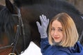 Portrait of a young girl with white hair next to a brown horse. The girl holds the horse and smiles. Close-up Royalty Free Stock Photo